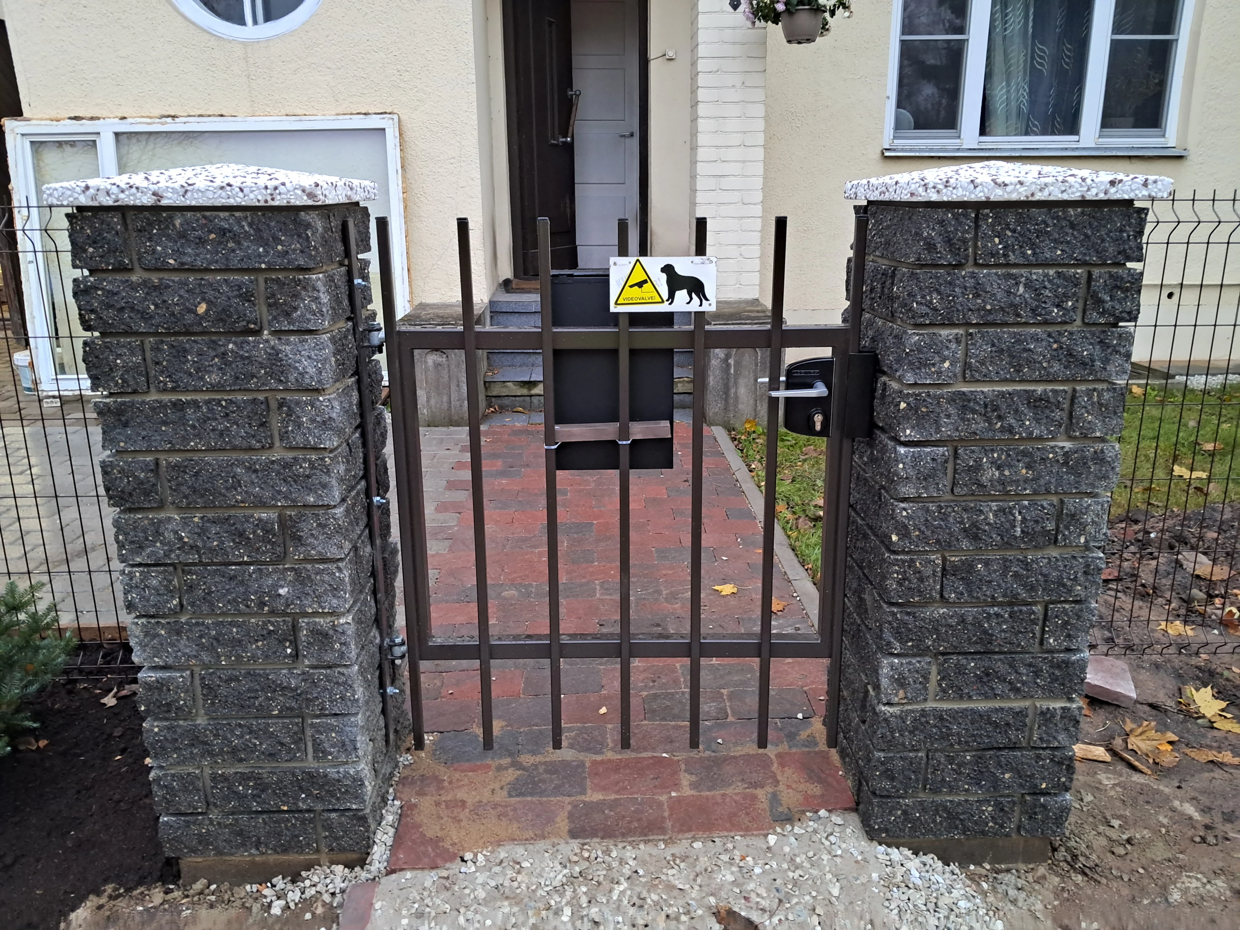 Kivipost - graniidist kiviposti vahele paigaldatud must metallvarbaed jalakäijavärav