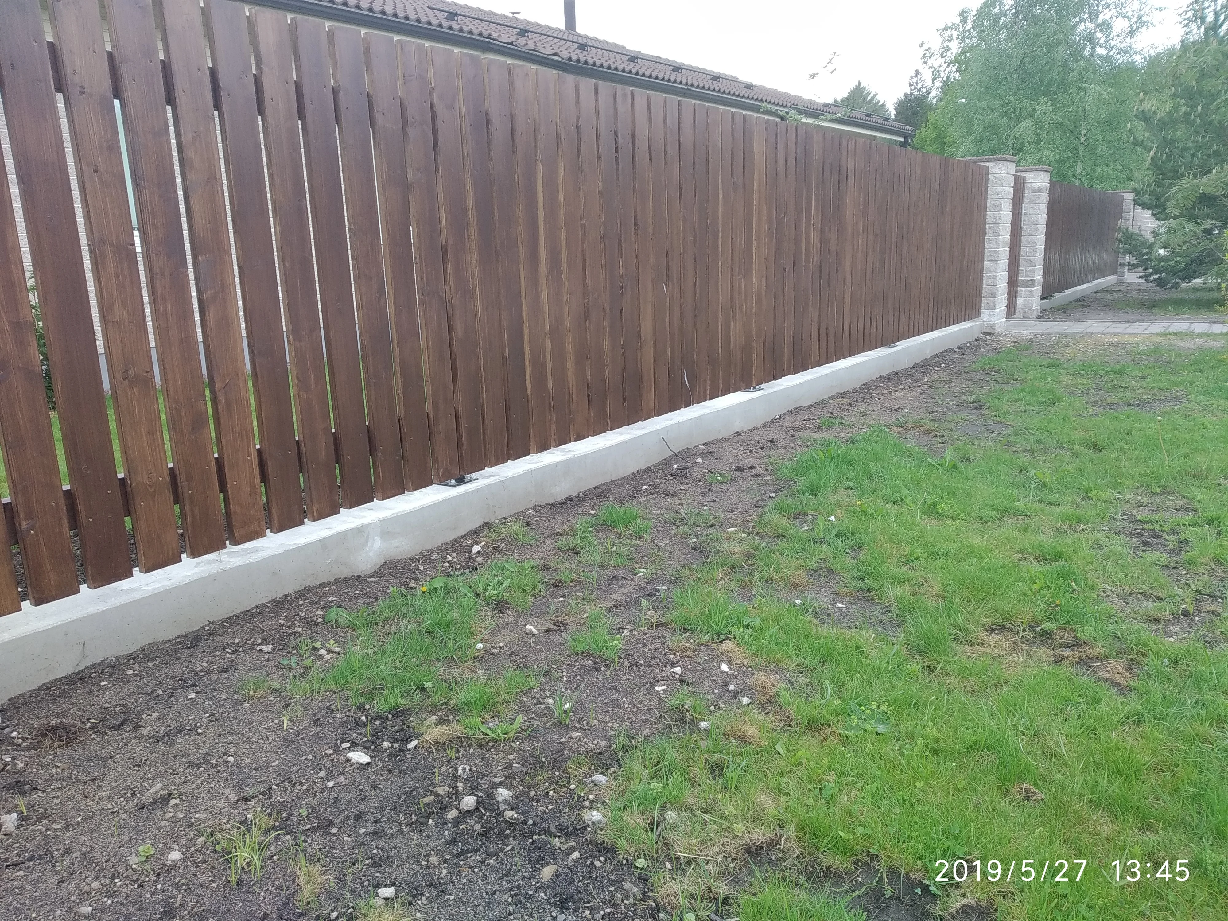 Kivipost - vertikaalne pruun puitaed betoonvundamendiga kiviseina kõrval