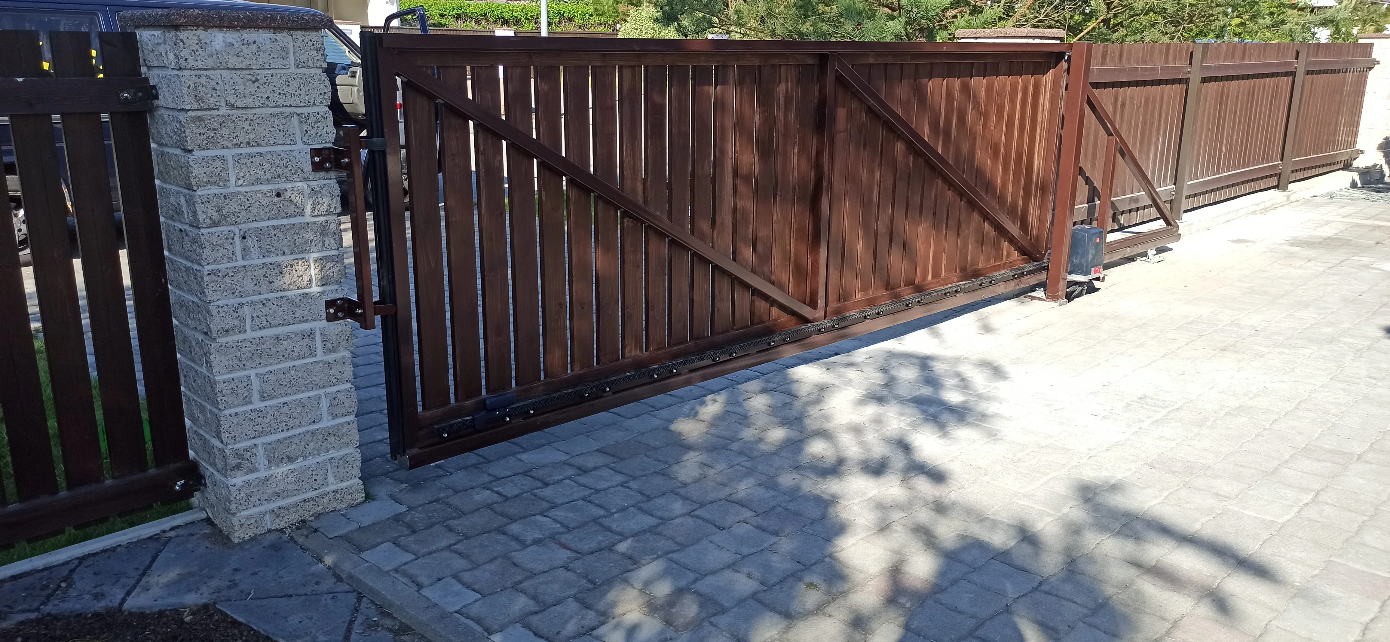 Kivipost - pruun puitlaudis liugvärav graniidist kiviposti kõrval