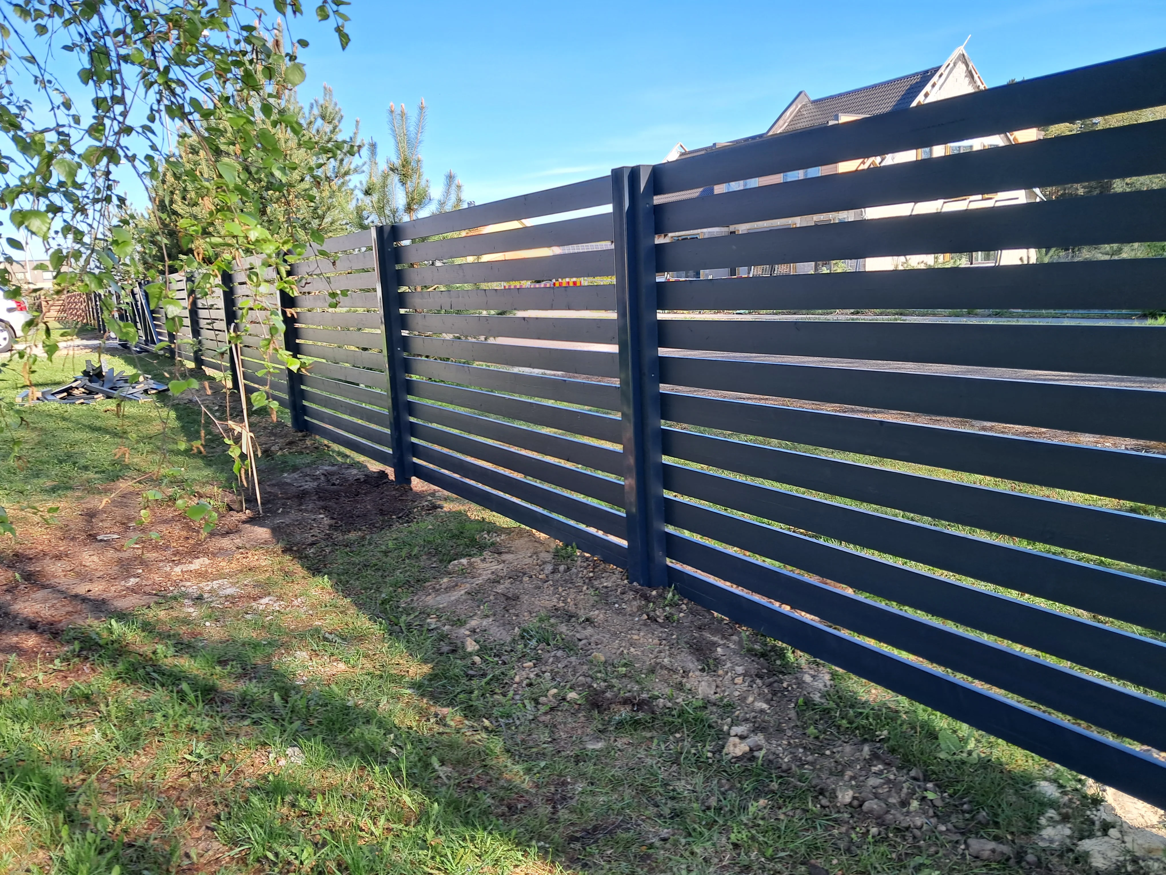 Puitaed - horisontaalne tumehall laudis metalpostidel eramu ümber