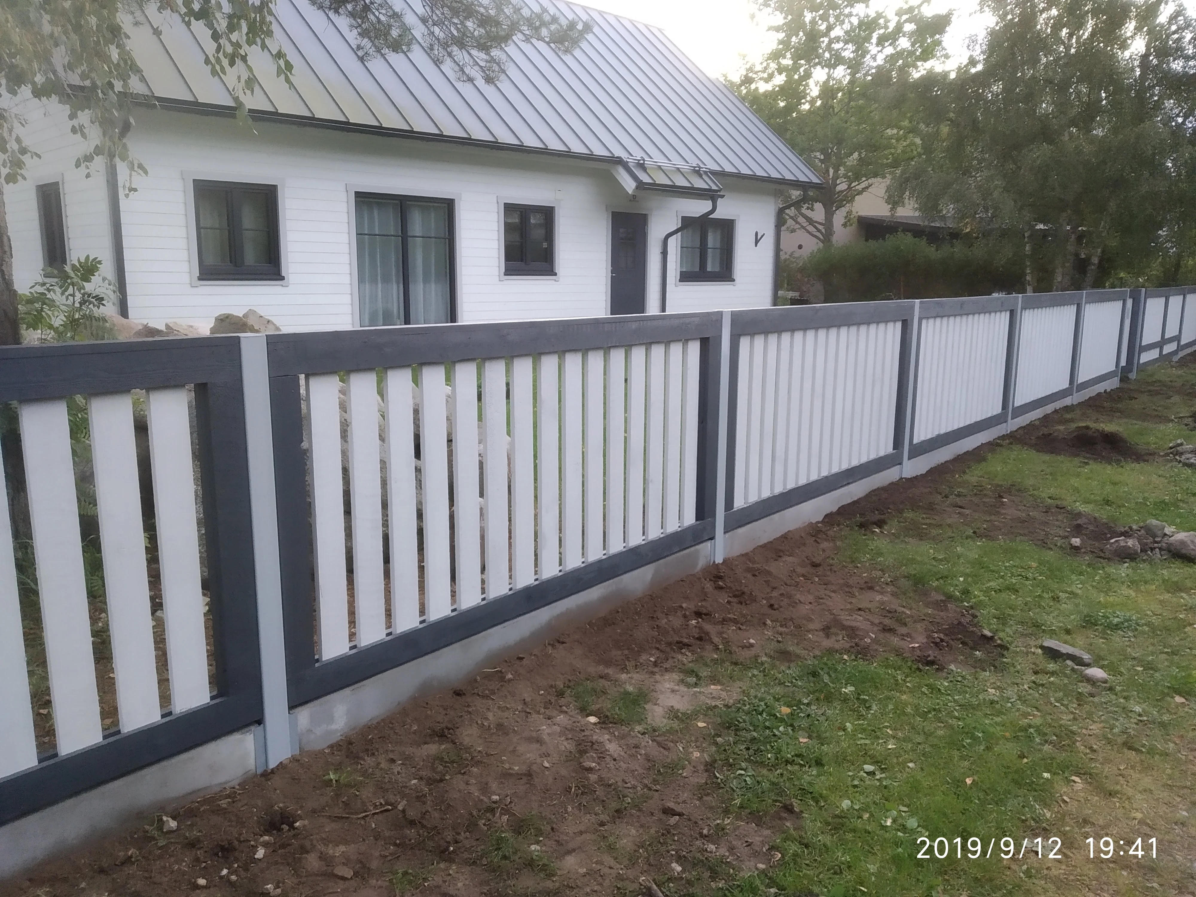 Puitaed - valge vertikaalne laudis antratsiitpostidega eramu hoovis